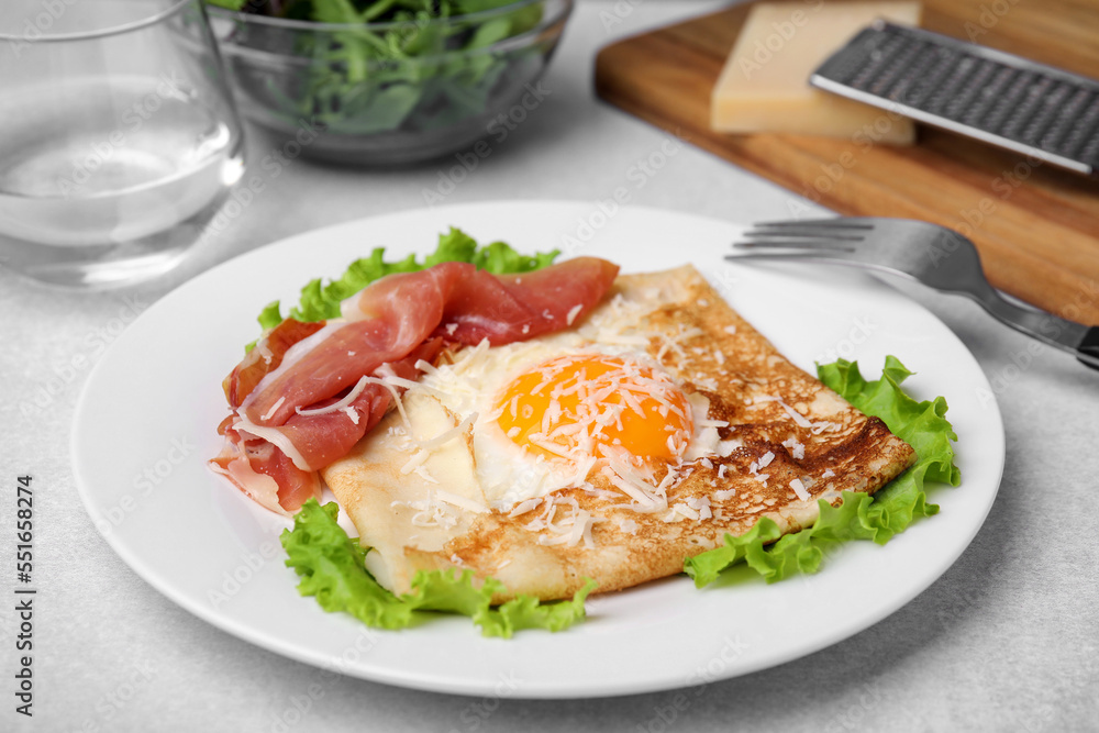 Delicious crepe with egg served on light gray table. Breton galette