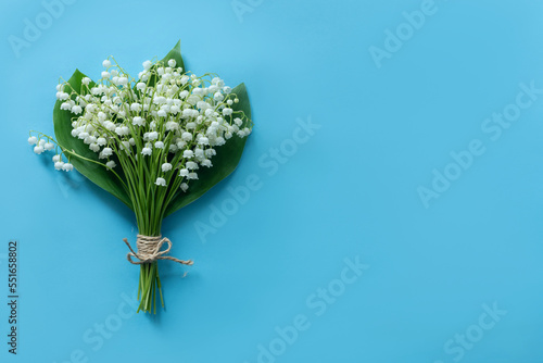 spring flowers lilies of the valley on a blue background, a bouquet of white lilies of the valley with place for text