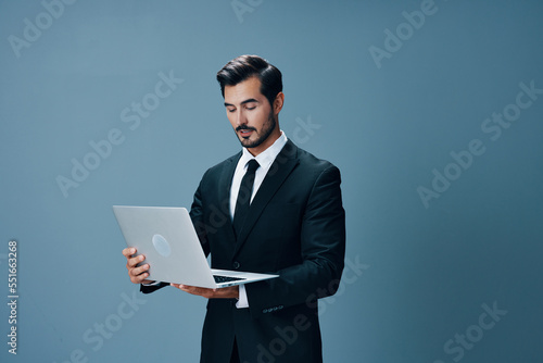 A business man looks at his laptop and works online via the internet in a business suit video call on a blue background