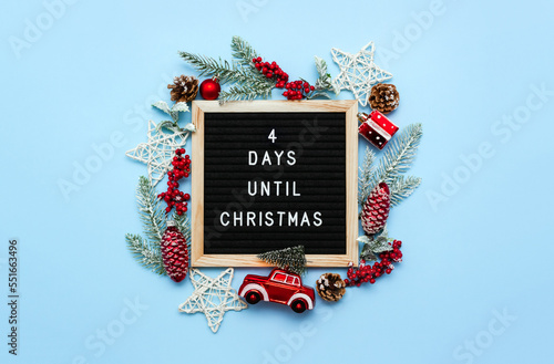 Felt letterboard with letters with countdown surrounded by winter seasonal decoration on blue background. 4 days until Christmas. Twenty-four day series of postcards. Selective focus