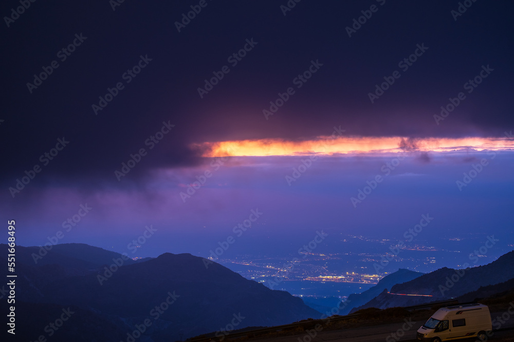 View of Sierra Nevada with small road and City of Granada at sunset
