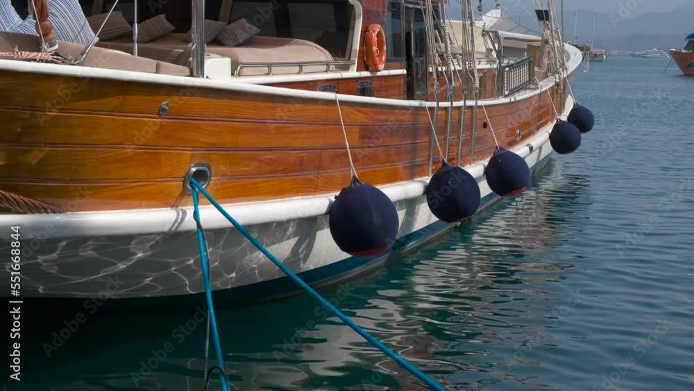 Wooden yacht against beach. A pretty modern wooden yacht moored against blue sea under sun. Wooden yacht against beach. A pretty modern wooden yacht moored against blue sea under sun.