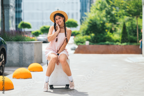 Young beautiful caucasian woman is sitting on suitecase photo