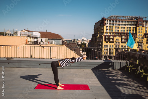 Woman doing yoga exercises on house roof in early morning