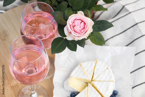 Glasses of delicious rose wine  flower and food on white picnic blanket