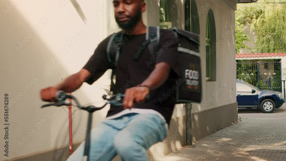 Restaurant employee arriving at customer front door to give takeaway meal, riding bike to deliver food order with backpack. Food delivery service courier delivering fastfood package on bicycle. Restaurant employee arriving at customer front door to give takeaway meal, riding bike to deliver food order with backpack. Food delivery service courier delivering fastfood package on bicycle.