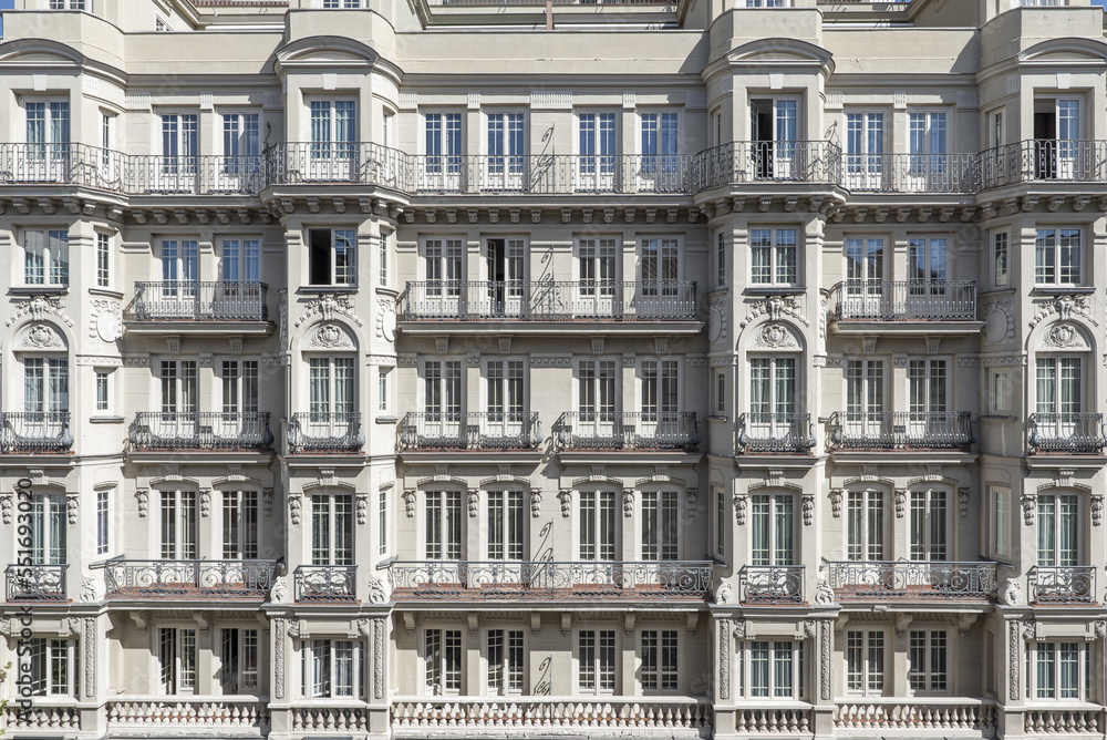 Facades of old stately urban residential apartment buildings with many balconies, bay windows and windows with balustrades and wrought iron railings on Calle Atocha in Madrid in Spain