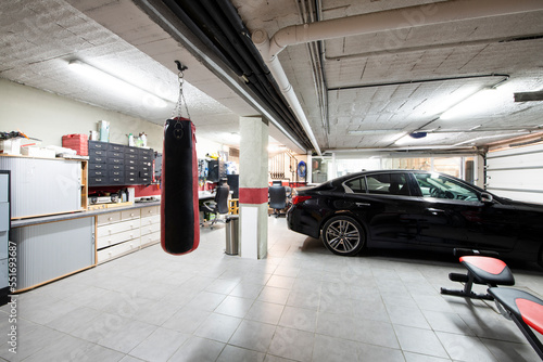 A detached house garage with gray floors, a punching bag and a parked luxury vehicle
