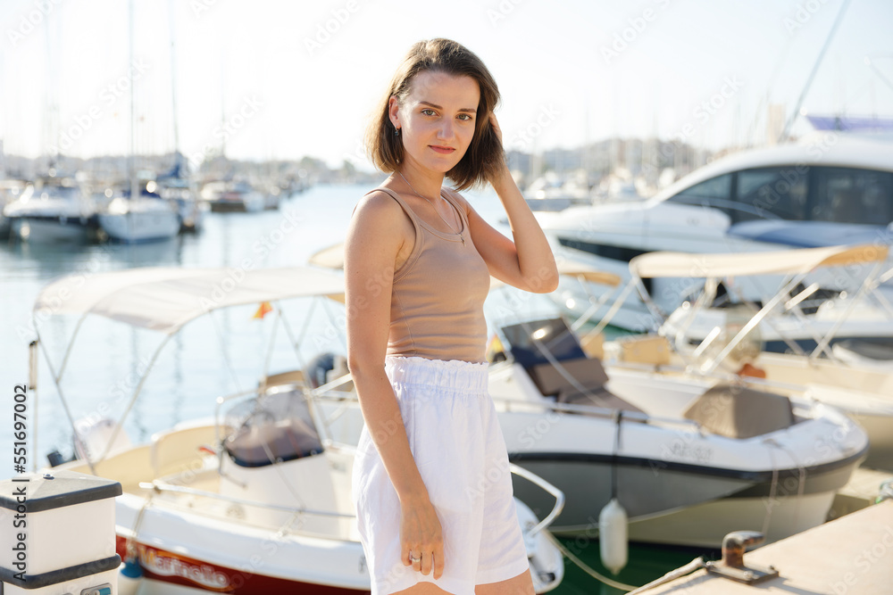 Obraz premium Beautiful woman in talking on the phone against the backdrop of the blue sea and yachts