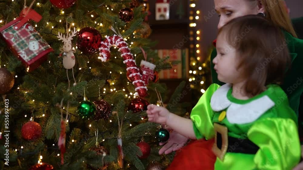 Happy mother with daughter touching Christmas tree, New year decorated Happy mother with daughter touching Christmas tree, New year decorated