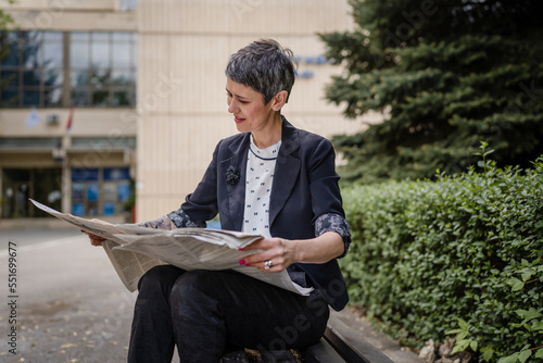 mature pensioner senior woman caucasian female read newspaper outdoor