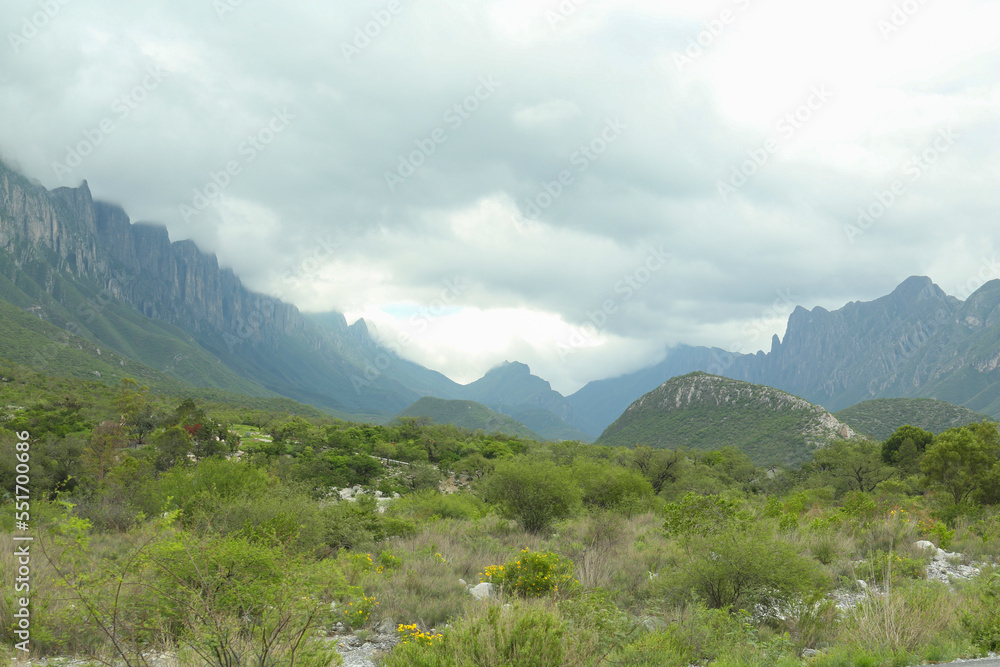 Picturesque landscape with high mountains and fog under cloudy sky