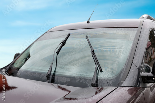 Car wipers cleaning water drops from windshield glass outdoors, closeup © New Africa