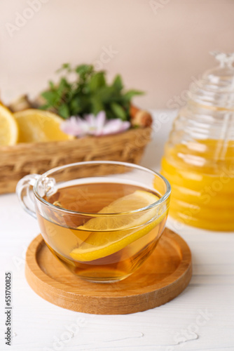 Cup of delicious tea with lemon and honey on white table