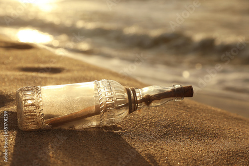 SOS message in glass bottle on sand near sea