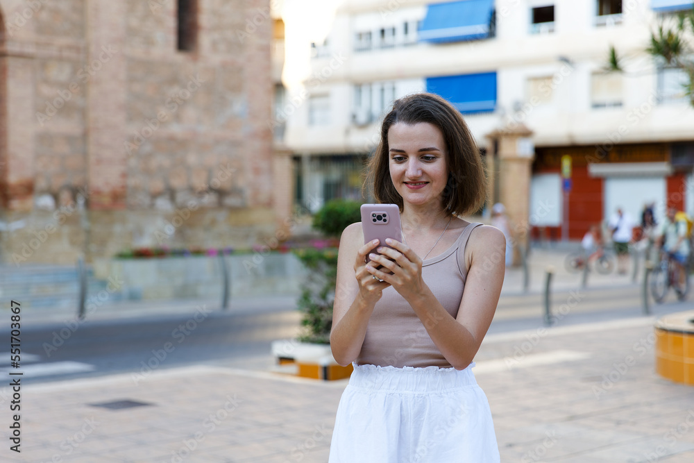 A young stylish woman communicates on a smartphone on a city street A young stylish woman communicates on a smartphone on a city street
