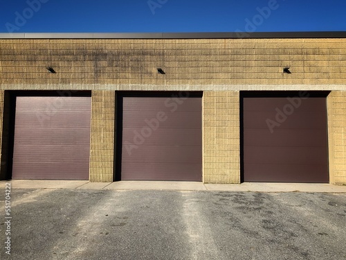 Minimal Three Option or Choices Decision Concept, Outdoor Closed Brown Garage Doors with Dirty Modern Brown Facade Cement Brick Wall & Lights Above on Industrial Manufacturing Storage Office Building