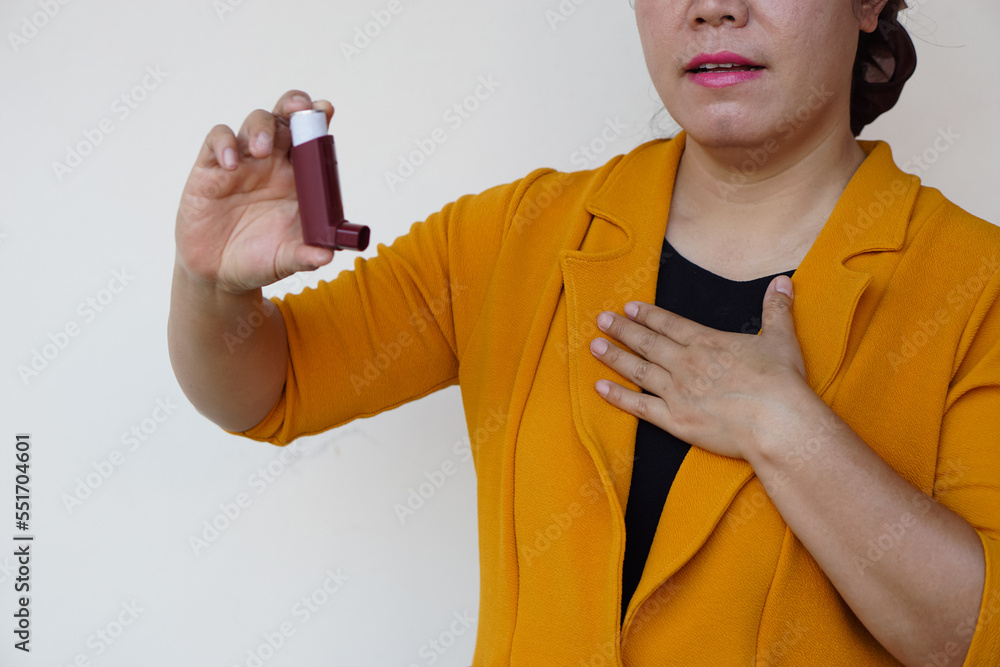 Closeup female patient uses brown asthma inhaler for relief asthma