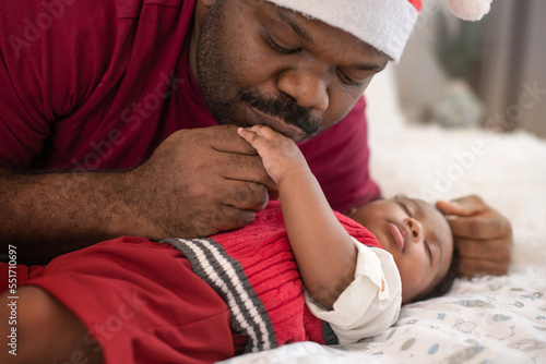 African father in santa hat kissing baby's hand while sleeping, lifestyle relationship concept, Christmas time