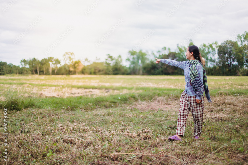 Young pretty farmer woman standing on farmland and inspecting agricultural crops