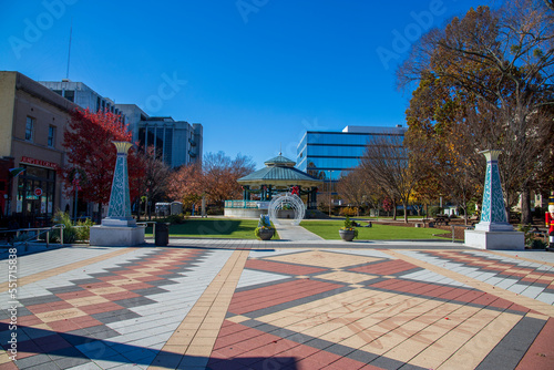 a gorgeous autumn landscape at the Decatur Square with red and yellow autumn trees, lush green trees and a round blue pergola, glass office buildings and clear blue sky in Decatur Georgia USA photo