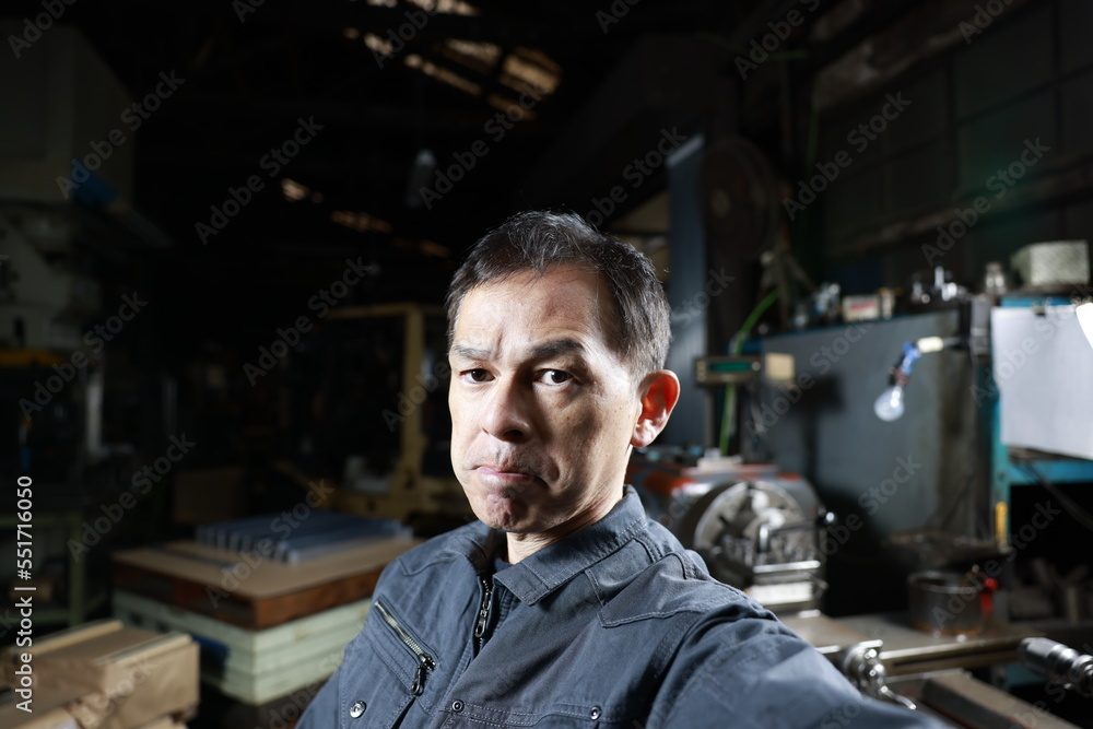 Metalworker in gray work clothes and a lathe in a small to medium-sized small business town factory. Conceptual images of the essence of manufacturing and technical succession. Metalworker in gray work clothes and a lathe in a small to medium-sized small business town factory. Conceptual images of the essence of manufacturing and technical succession.