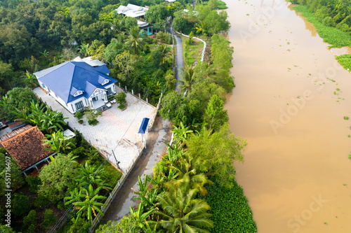 aerial view of Villa house in the middle of the garden with blue tile roof and the river at Mekong river delta VietNam countryside, Thai house building style. 