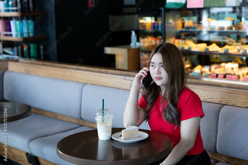 A woman talking on phone with friend while eating cake and drink in restaurant A woman talking on phone with friend while eating cake and drink in restaurant