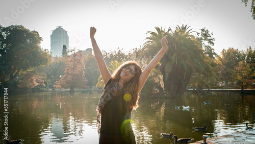 Wallpaper Mural Girl woman in a park rising her arms with long curly hair dressed in brown with sunbeams in the back and nature colors sleepy happy yawn Torontodigital.ca