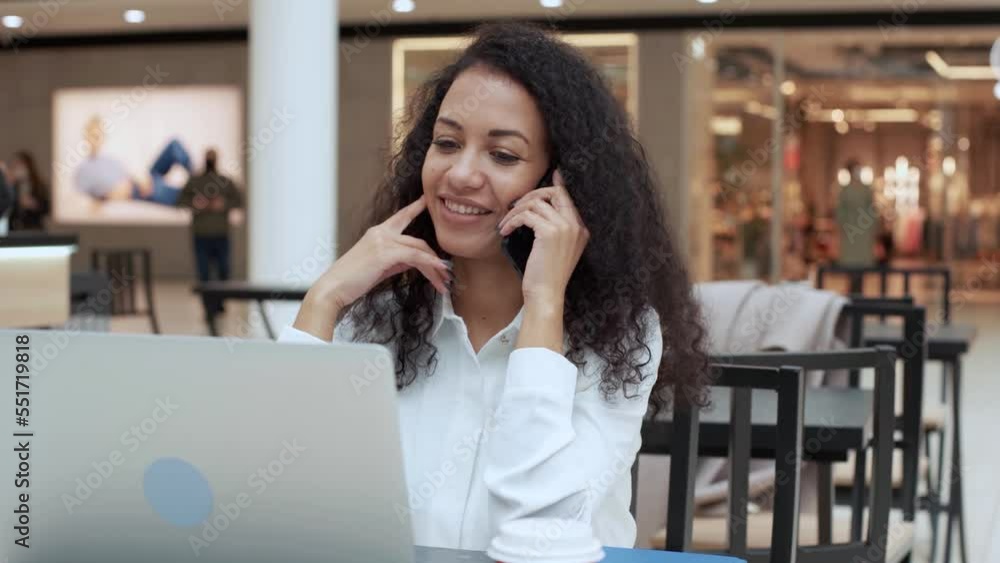 young woman using a laptop and talking on a smartphone. young woman using a laptop and talking on a smartphone.