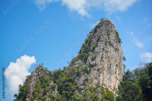A high-vertical limestone mountain cliff on blue sky background. Nature outdoor scene photo.