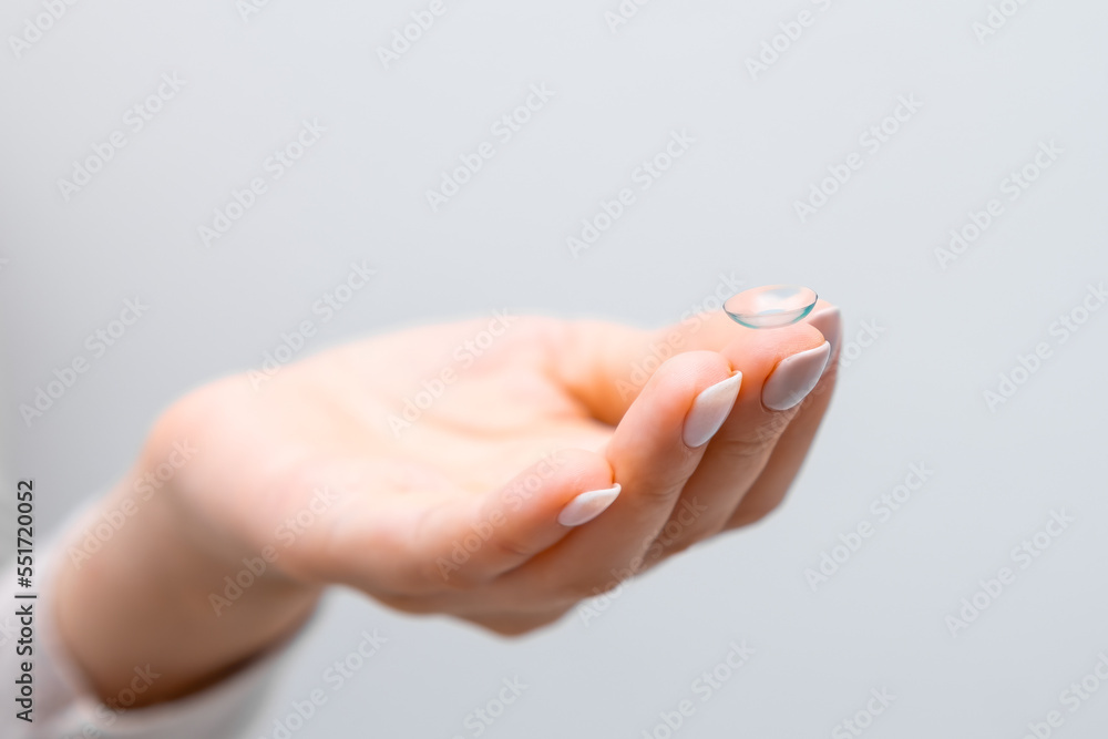 Close up woman hand with contact lens on the grey background Close up woman hand with contact lens on the grey background