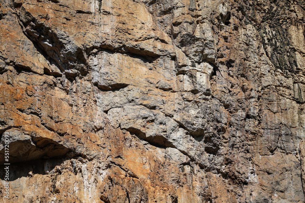 Rough rock formation structure of limestone mountain cliff wall.