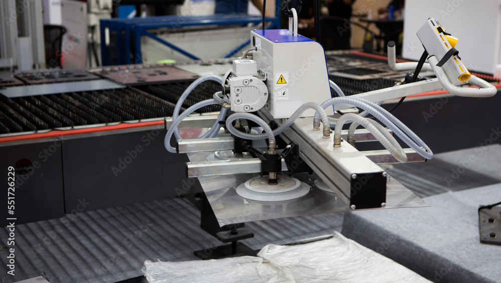 Mechanical vacuum metal sheet lifter loading metal sheet to CNC laser cutting machine. Industrial manufacture.