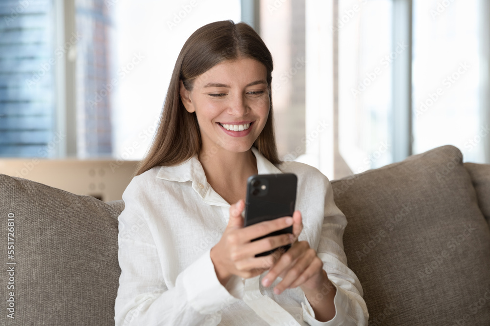 Happy pretty young smartphone user woman talking on video call on mobile phone, sitting on home couch, holding cellphone, smiling at screen, using online app for communication Happy pretty young smartphone user woman talking on video call on mobile phone, sitting on home couch, holding cellphone, smiling at screen, using online app for communication