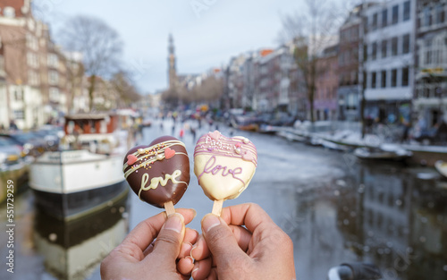 Canvas Print City trip Amsterdam during Valentine's with love romantic ice cream and on the background people ice skating at the frozen canals of Amsterdam, Valentine Romantic concept