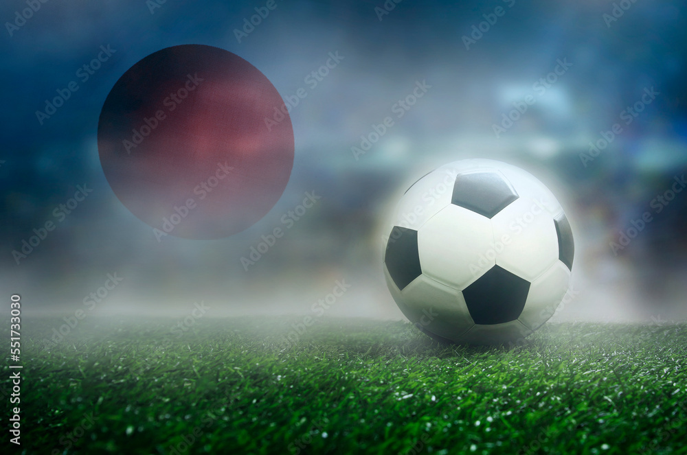 Naklejka premium Football and Japan Flag on Green Field