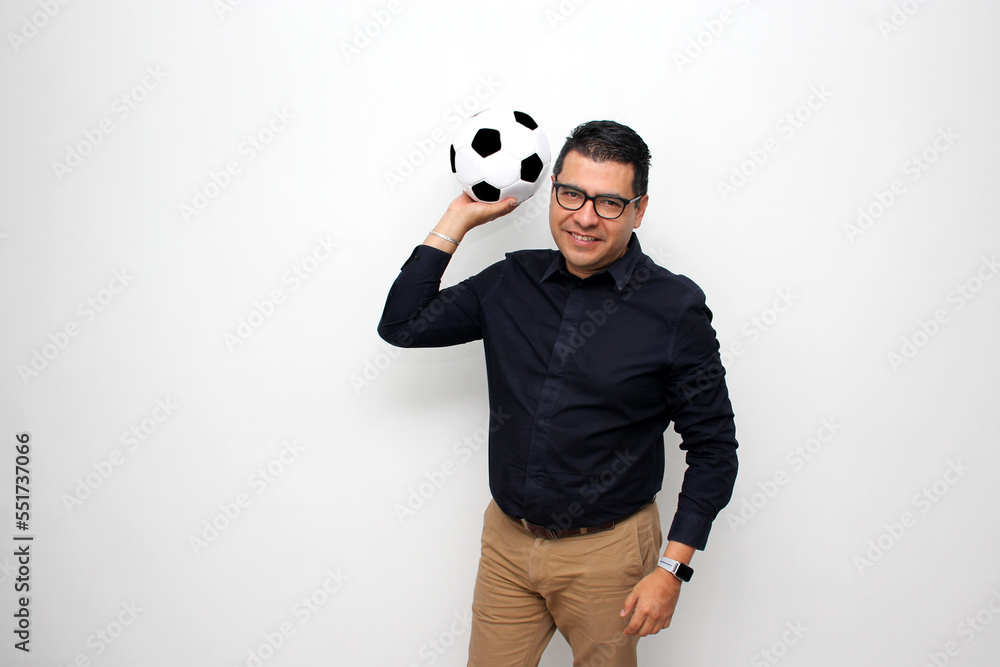 Fototapeta premium Latino adult office man plays with a soccer ball very excited that he is going to see the game and wants to see his team win