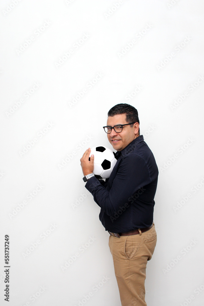 Fototapeta premium Latino adult office man plays with a soccer ball very excited that he is going to see the game and wants to see his team win