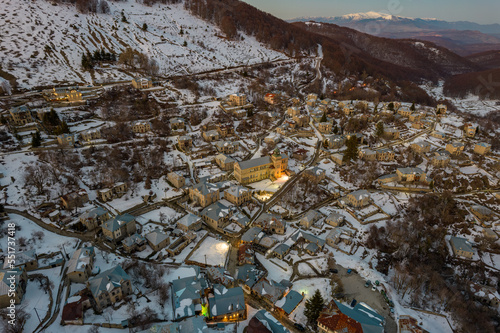 Aerial view of traditional architecture  with  stone buildings and the famous local school with a label in front. tranlation Nikios(name ) school in the snowy village of Nymfaio  Florinas Greece photo