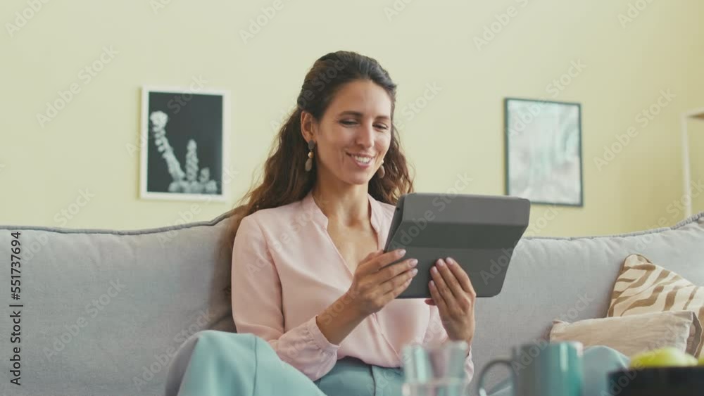Delighted young brunette woman having video chat with friend on tablet PC while staying in modern apartment Delighted young brunette woman having video chat with friend on tablet PC while staying in modern apartment