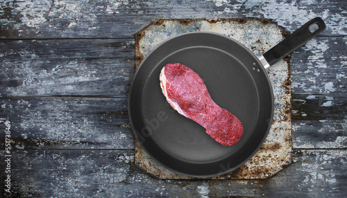 Cut of meat in the shape of shoe sole on pan. Poor quality meat concept. Tough meat. Overhead shot. photo