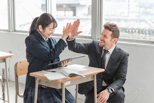 学校・塾でタブレットを使って楽しく英語を学ぶ高校生・中学生と指導する笑顔の外国人講師（ICT教育）
