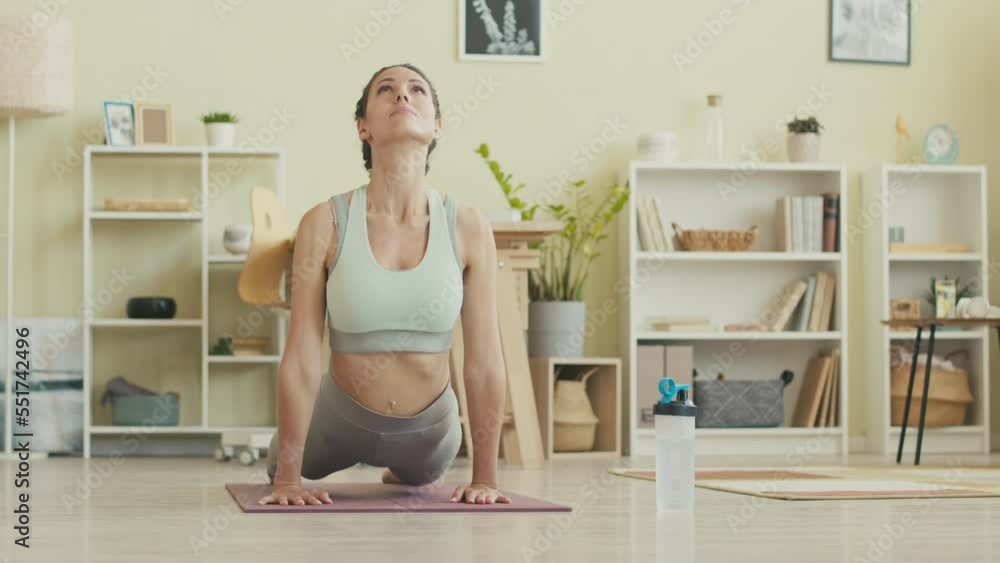 Young Caucasian woman in tight activewear doing upward facing dog pose while practicing yoga asanas on mat at home Young Caucasian woman in tight activewear doing upward facing dog pose while practicing yoga asanas on mat at home