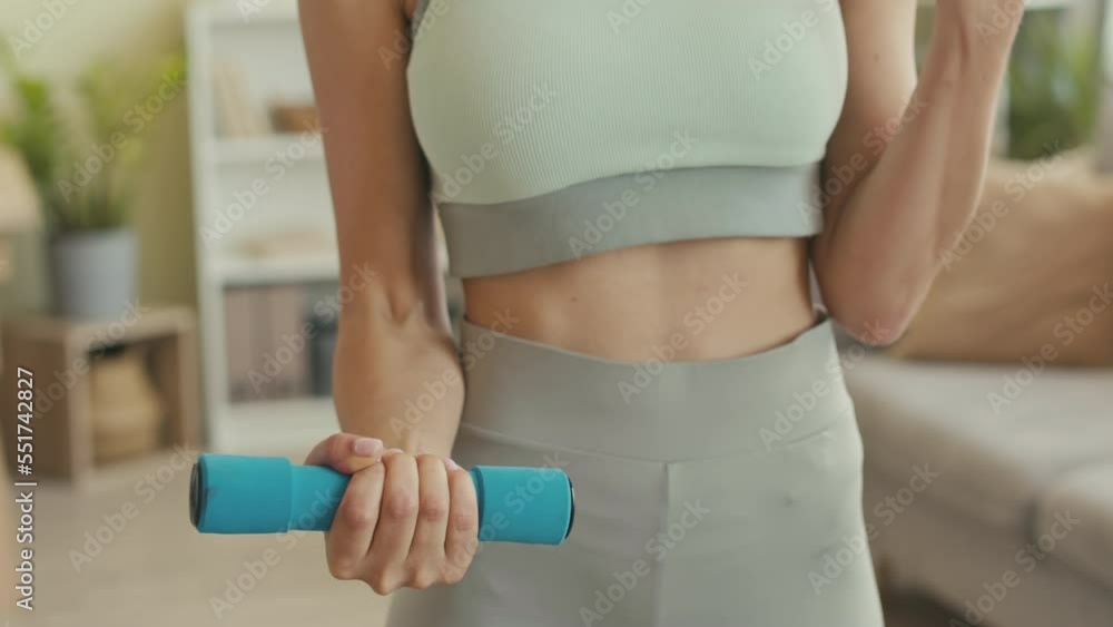 Cropped shot of unrecognizable fit woman in tight sportswear lifting dumbbells at home Cropped shot of unrecognizable fit woman in tight sportswear lifting dumbbells at home