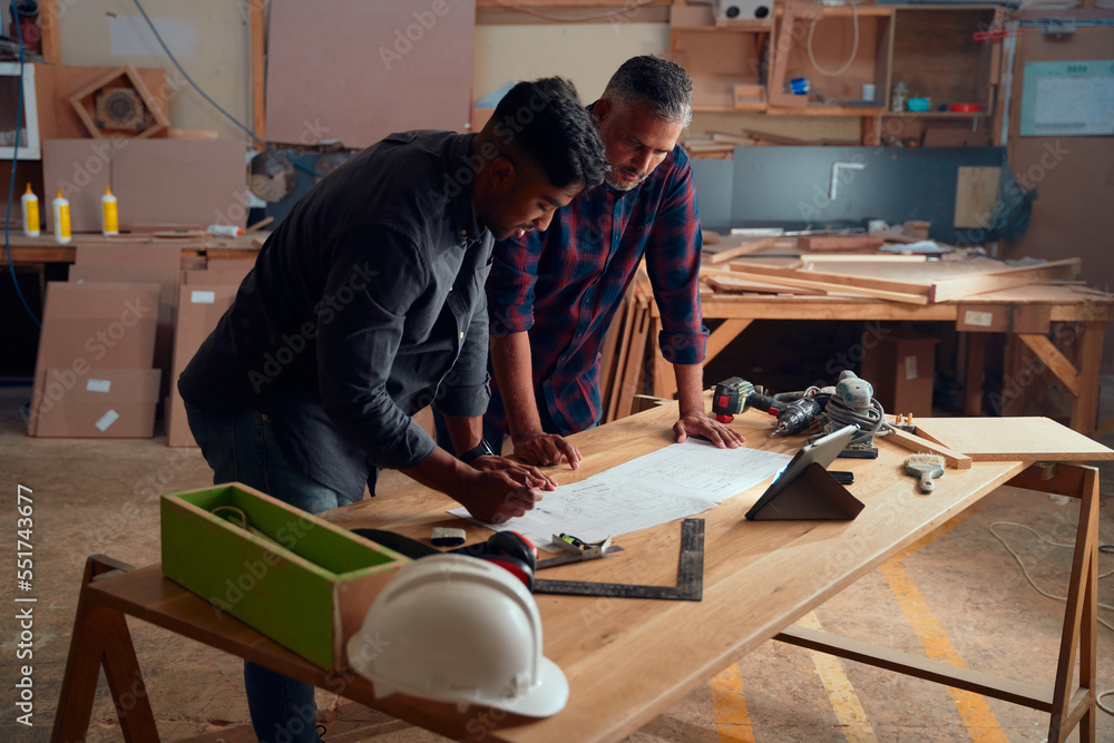 Men writing on paper on top of table with digital tablet and tools in woodworking factory Men writing on paper on top of table with digital tablet and tools in woodworking factory