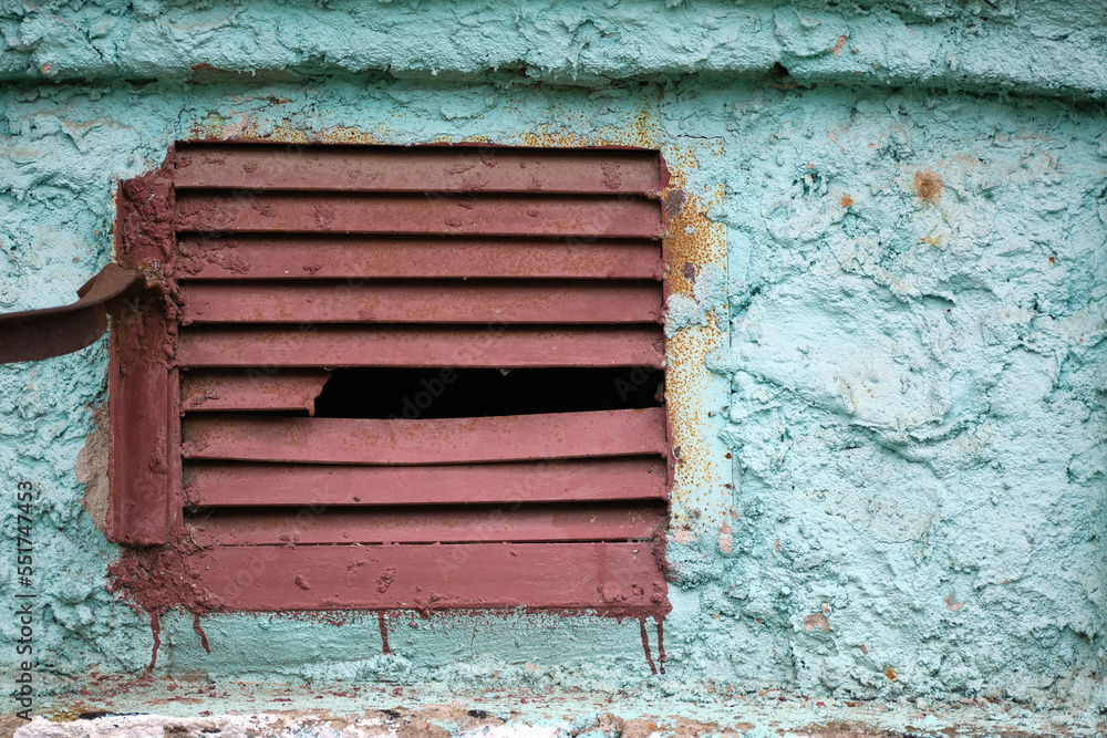 Old brown metal grating with a broken compartment in a concrete wall. Abstract background Old brown metal grating with a broken compartment in a concrete wall. Abstract background