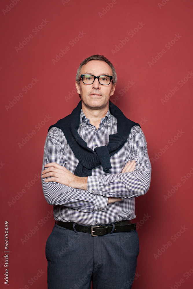 Mature businessman with grey hair in checked shirt and glasses on red background