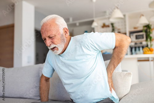 Senior elderly man touching his back, suffering from backpain, sciatica, sedentary lifestyle concept. Spine health problems. Healthcare, insurance