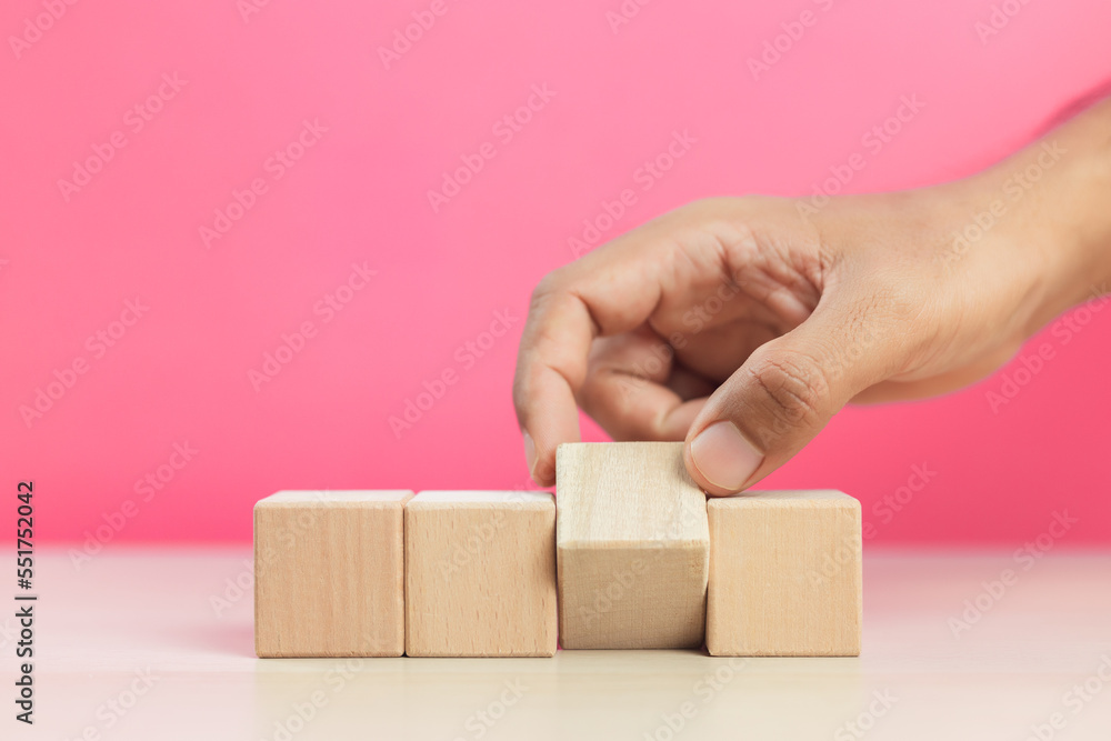 Concept of education and development. Hand flip blank wooden cube block sort on table pink background use for create text or symbol. growth success. Concept of education and development. Hand flip blank wooden cube block sort on table pink background use for create text or symbol. growth success.